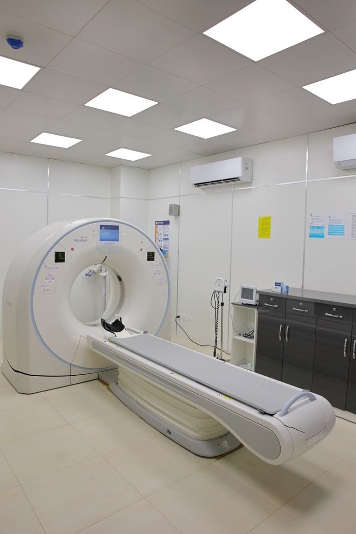 A modern CT scan machine in a well-lit, sterile hospital room for diagnostic imaging.